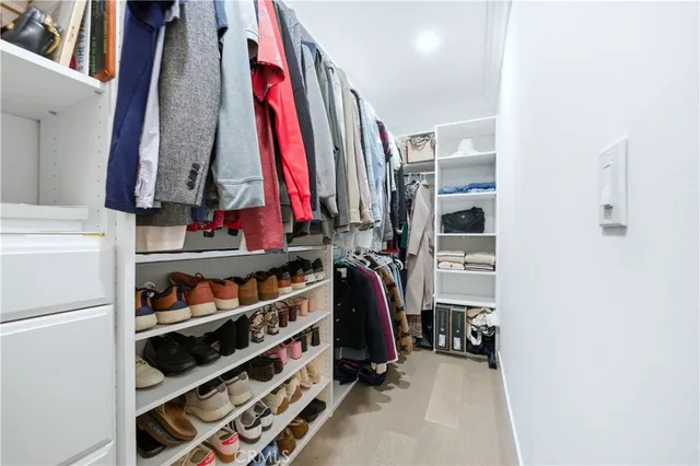 a view of walk in closet with clothes and shoes