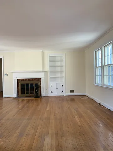 an empty room with wooden floor fireplace and windows
