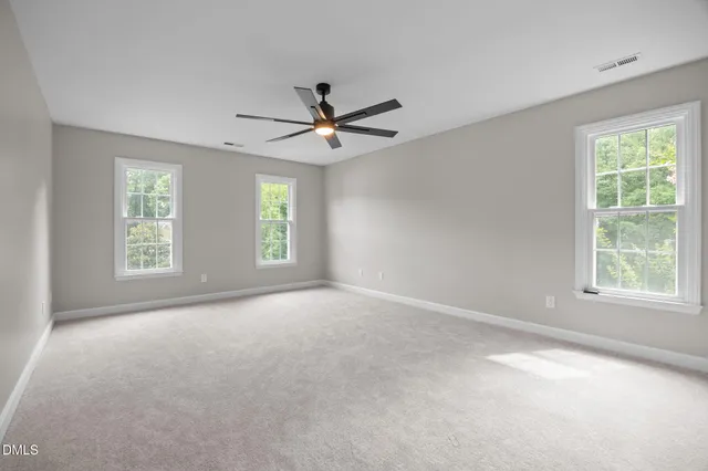an empty room with windows and ceiling fan