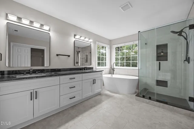 a spacious bathroom with double vanity a mirror a bathtub and a shower