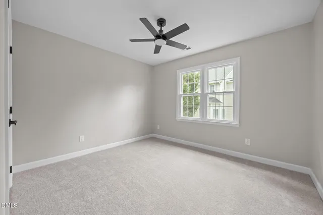 an empty room with ceiling fan and windows