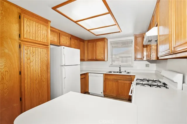 a kitchen with stainless steel appliances granite countertop a refrigerator a sink dishwasher a stove and a dining table with wooden cabinet