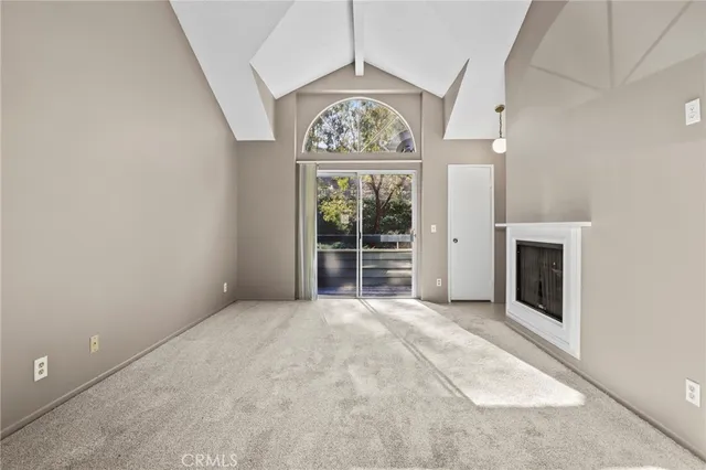 a view of an empty room with a fireplace and a window