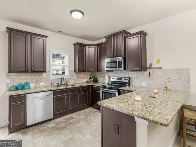 a kitchen with kitchen island granite countertop stainless steel appliances and sink
