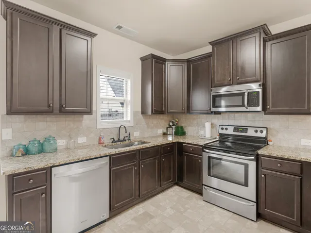 a kitchen with stainless steel appliances granite countertop a sink stove oven and refrigerator
