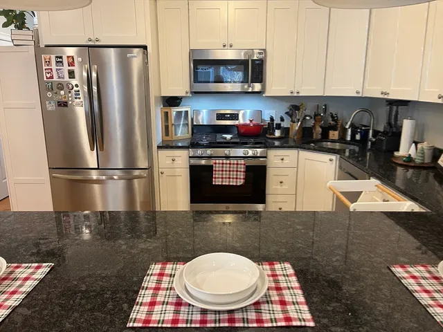 a kitchen with stainless steel appliances granite countertop a refrigerator a stove a sink and a microwave