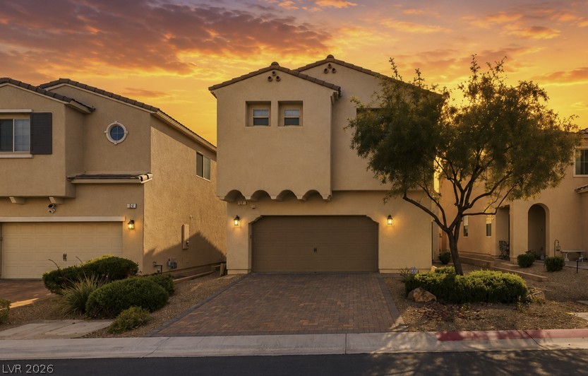 32 Lily Grove Road Las Vegas, NV 89148 - Photo 1 of 53 A well-maintained facade with a paver driveway, illuminated by the warm glow of dusk.