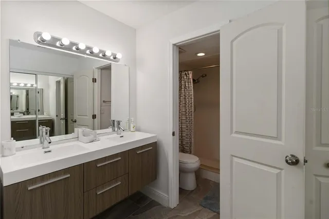 a bathroom with a double vanity sink a toilet and a mirror