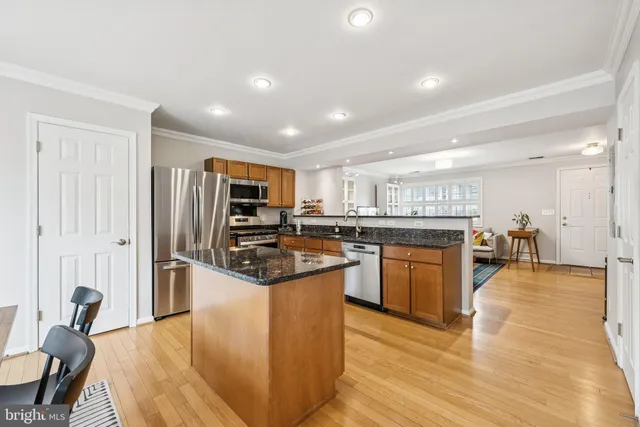 a kitchen with stainless steel appliances granite countertop a refrigerator a stove top oven a sink dishwasher and cabinets with wooden floor