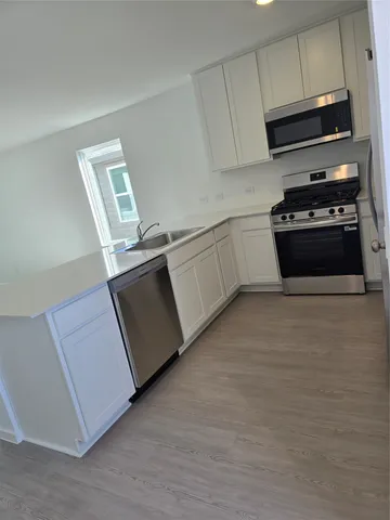 a kitchen with stainless steel appliances a stove microwave and sink