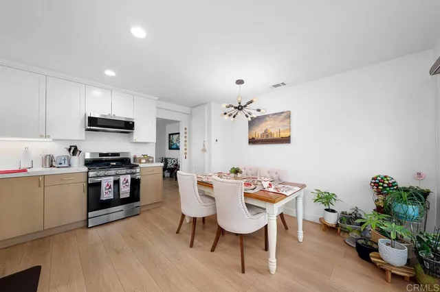 a kitchen with stainless steel appliances granite countertop a stove top oven a sink a dining table and chairs with wooden floor