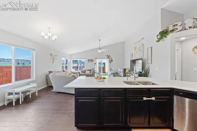 a kitchen with stainless steel appliances kitchen island granite countertop a dining table chairs stove and white cabinets