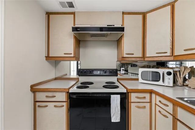 a kitchen with stainless steel appliances granite countertop a stove a sink and white cabinets