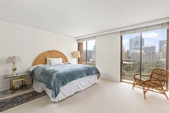 a spacious bedroom with a bed a table and large windows