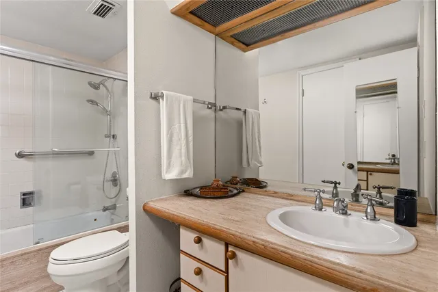 a bathroom with a granite countertop sink a toilet and shower