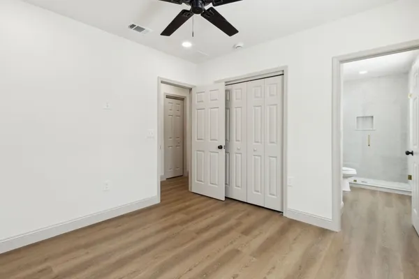 an empty room with wooden floor ceiling fan and windows