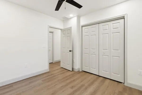 an empty room with wooden floor cabinet and windows