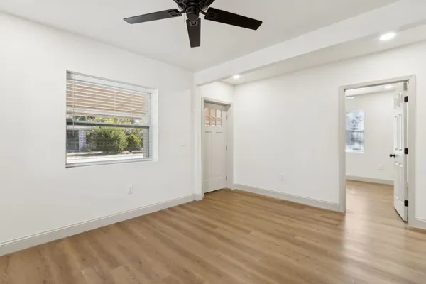 a view of an empty room with wooden floor and a window