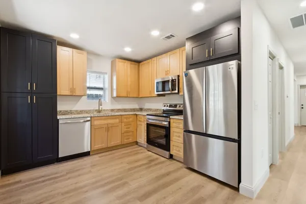 a kitchen with a refrigerator stainless steel appliances wooden floor cabinets
