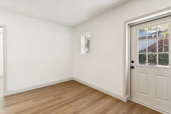 an empty room with wooden floor and windows