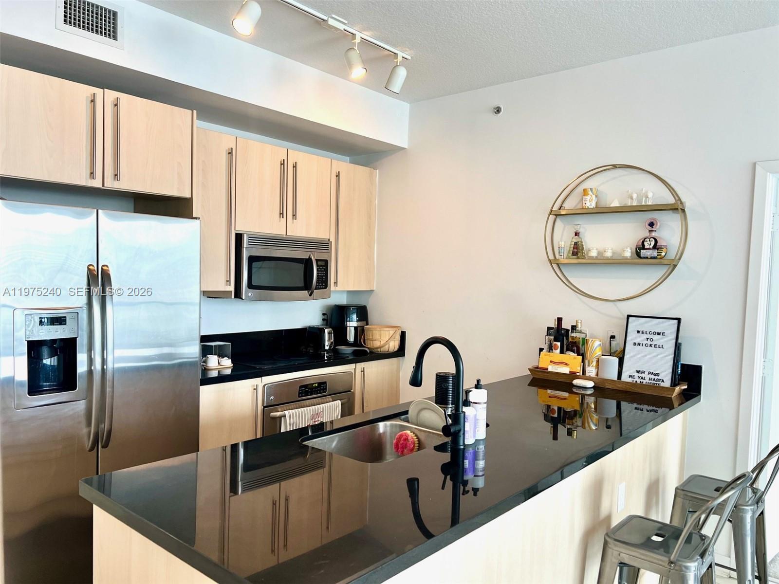 a kitchen with stainless steel appliances granite countertop a sink refrigerator and microwave