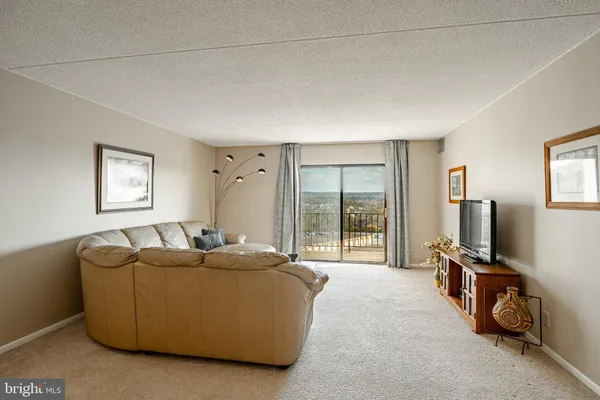 a living room with furniture a flat screen tv and a floor to ceiling window