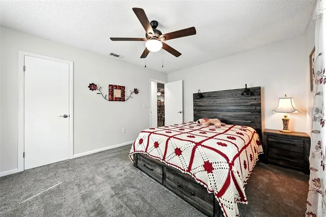 a bedroom with a bed next to a window with the potted plants on the dresser