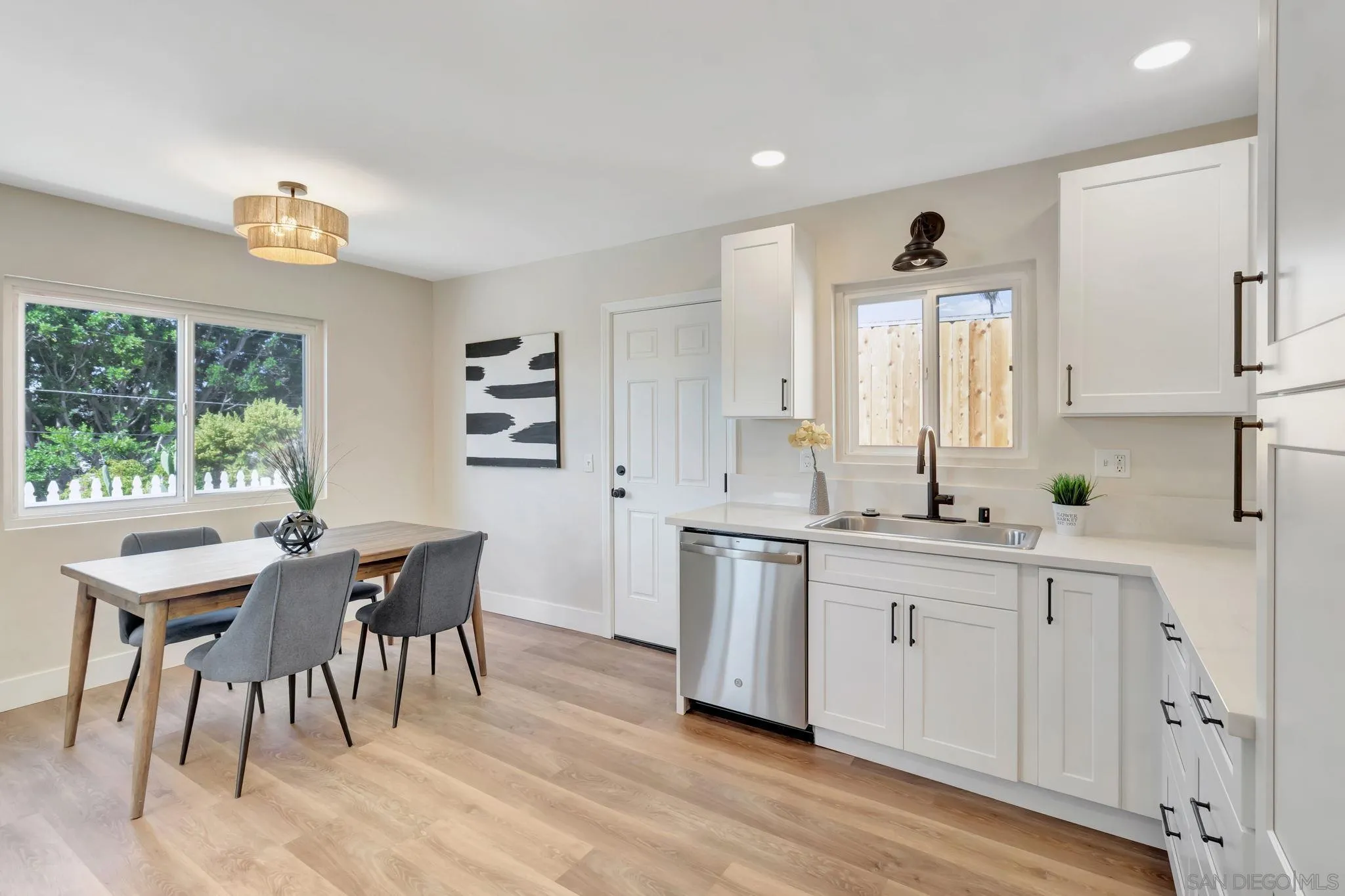 9188 Valencia Street Spring Valley, CA 91977 - Photo 13 of 27 a kitchen with white cabinets a sink dining table and chairs