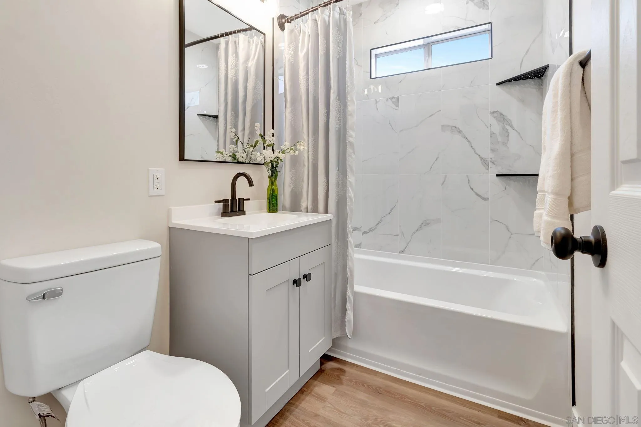 9188 Valencia Street Spring Valley, CA 91977 - Photo 21 of 27 a bathroom with a sink a toilet and a mirror