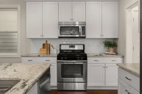 a kitchen with granite countertop white cabinets and white appliances
