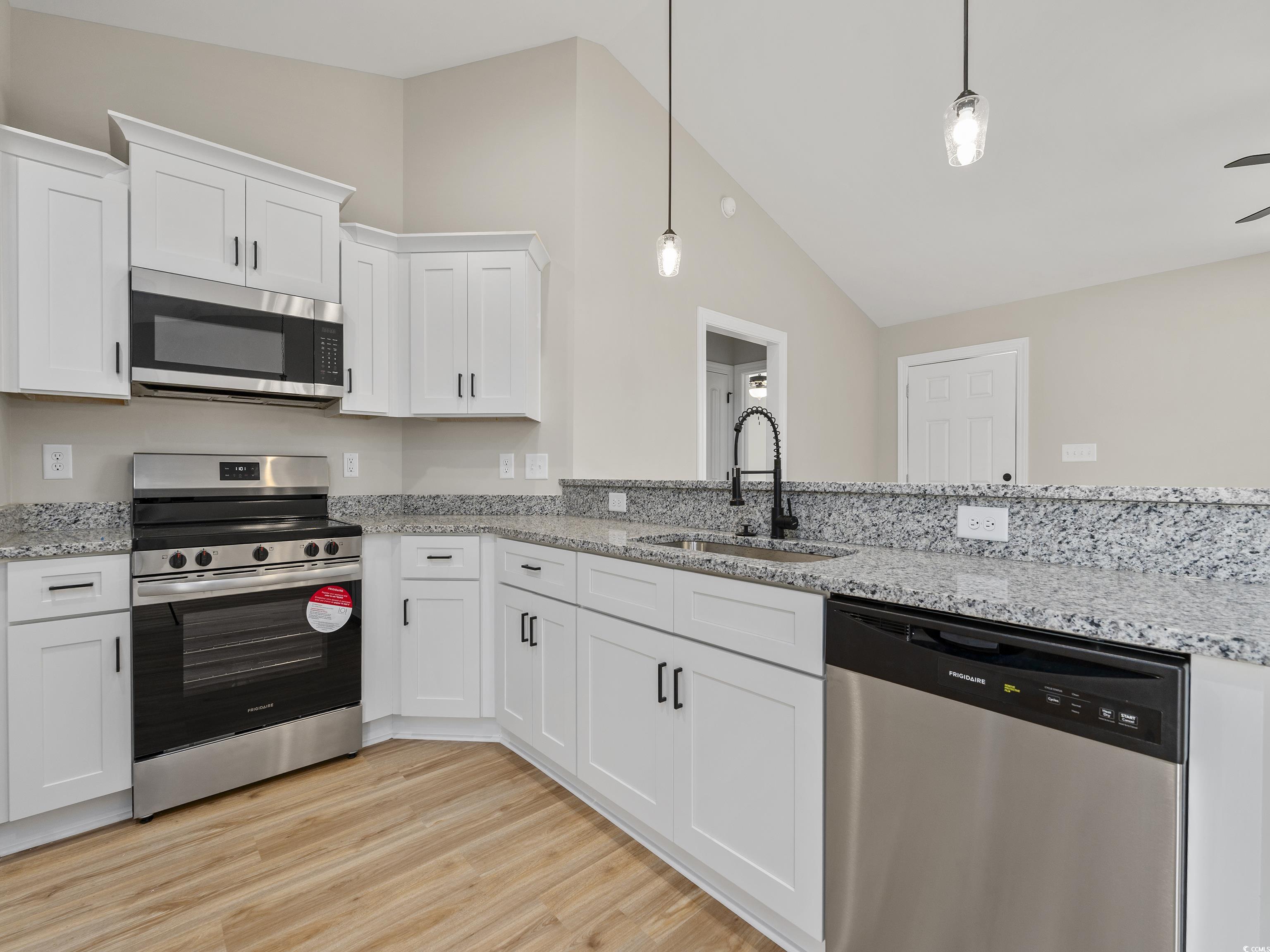 849 Highway 67 Loris Sc 29569 Loris, SC 29569 - Photo 10 of 28 Kitchen with white cabinets, a sink, light wood-type flooring, vaulted ceiling, and stainless steel appliances