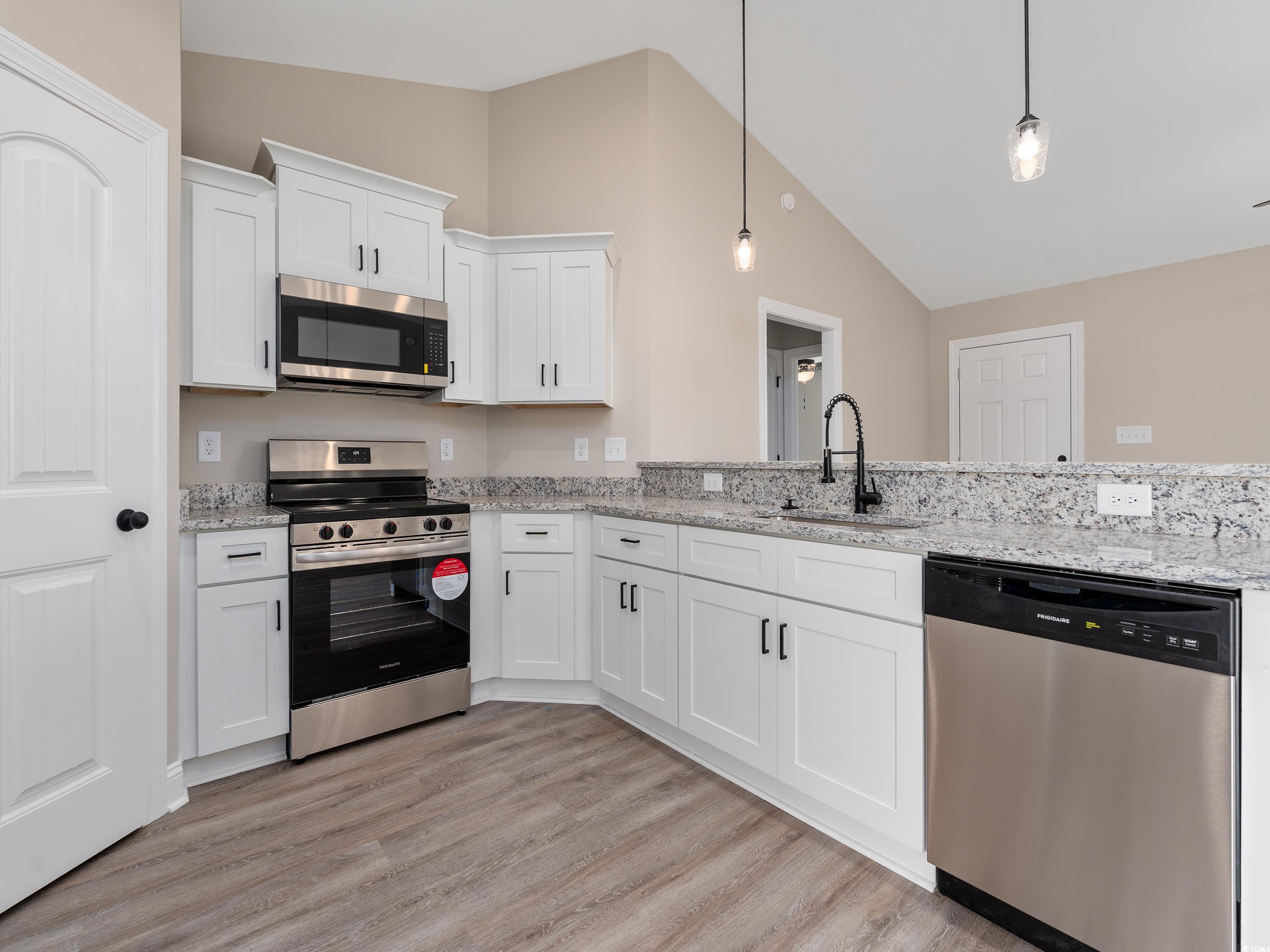 849 Highway 67 Loris Sc 29569 Loris, SC 29569 - Photo 12 of 28 Kitchen with white cabinetry, vaulted ceiling, a sink, stainless steel appliances, and light wood finished floors