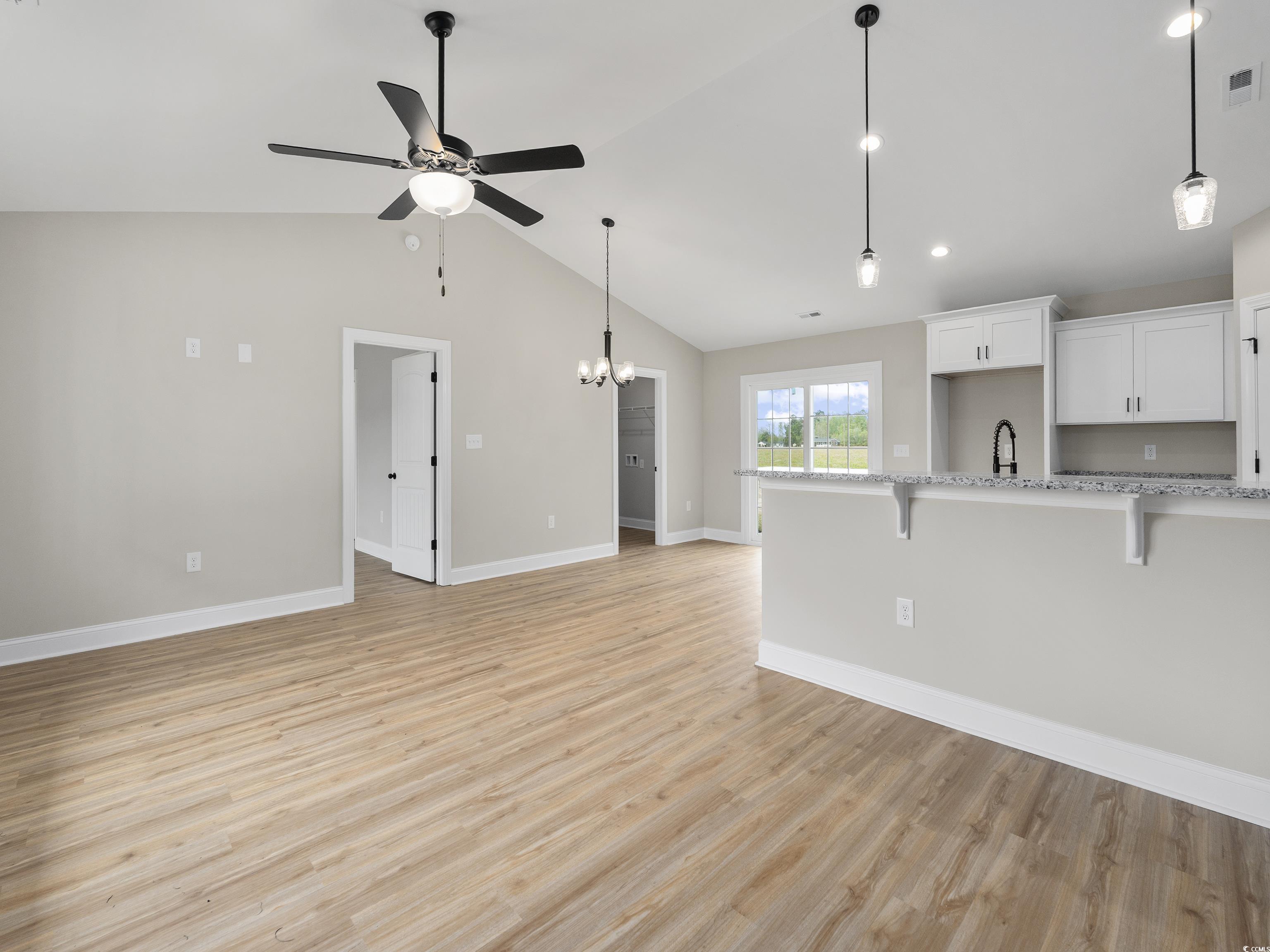 849 Highway 67 Loris Sc 29569 Loris, SC 29569 - Photo 8 of 28 Unfurnished living room featuring baseboards, vaulted ceiling, light wood-style flooring, visible vents, and ceiling fan with notable chandelier