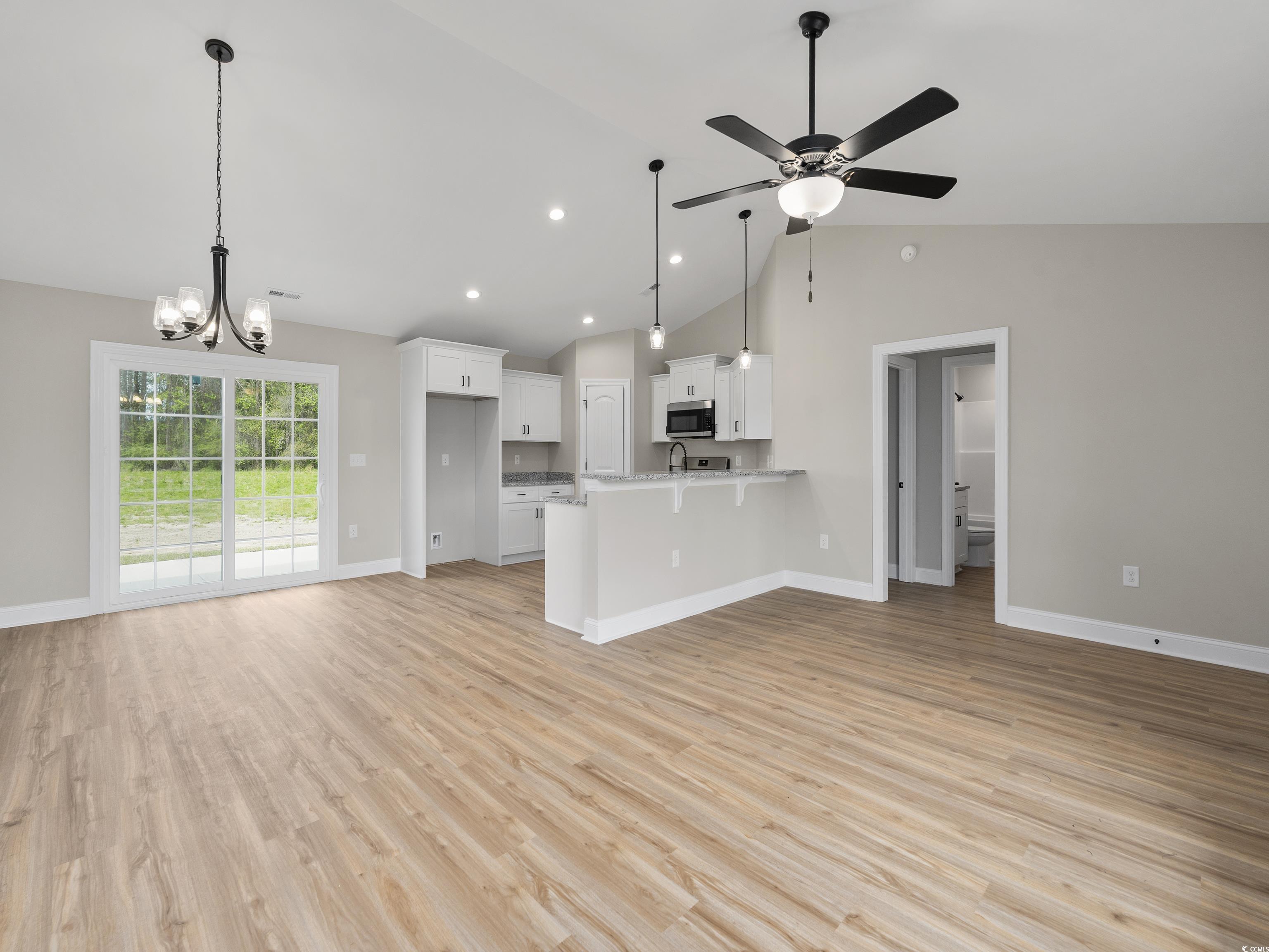 849 Highway 67 Loris Sc 29569 Loris, SC 29569 - Photo 27 of 28 Kitchen with stainless steel microwave, open floor plan, a peninsula, white cabinetry, and light wood finished floors