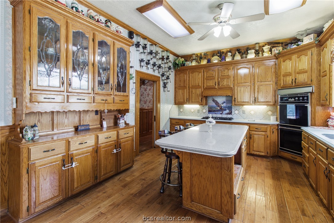 106 South Logan Avenue Bryan, TX 77803 - Photo 20 of 47 a kitchen with stainless steel appliances kitchen island granite countertop a stove a sink dishwasher and white cabinets with wooden floor