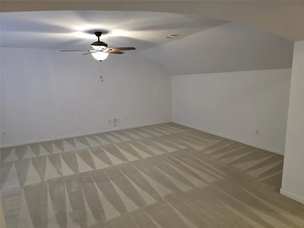 an empty room with a chandelier fan and wooden floor