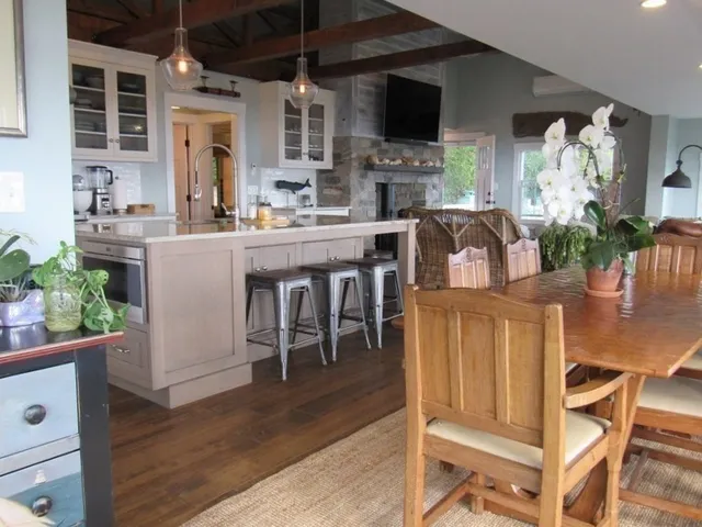 a kitchen with stainless steel appliances kitchen island granite countertop a table chairs and a stove