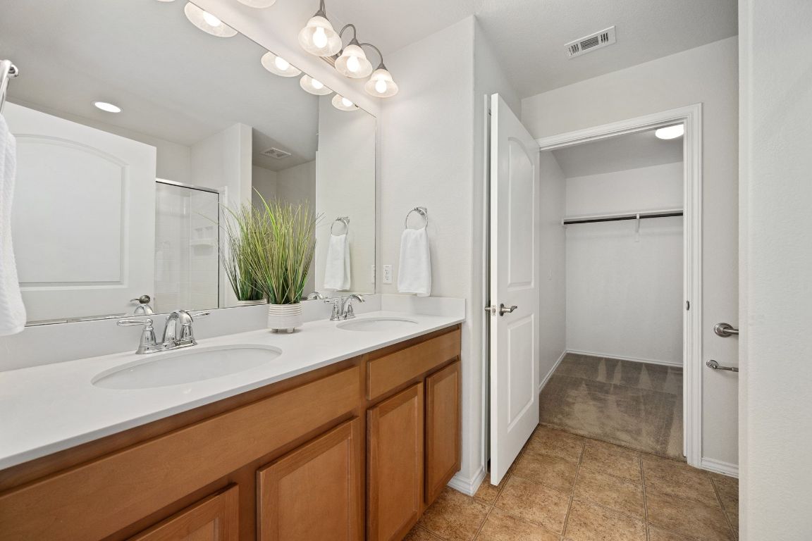 225 Hobby Street Georgetown, TX 78633 - Photo 16 of 40 a en suite bathroom with a double vanity sink a mirror and a shower