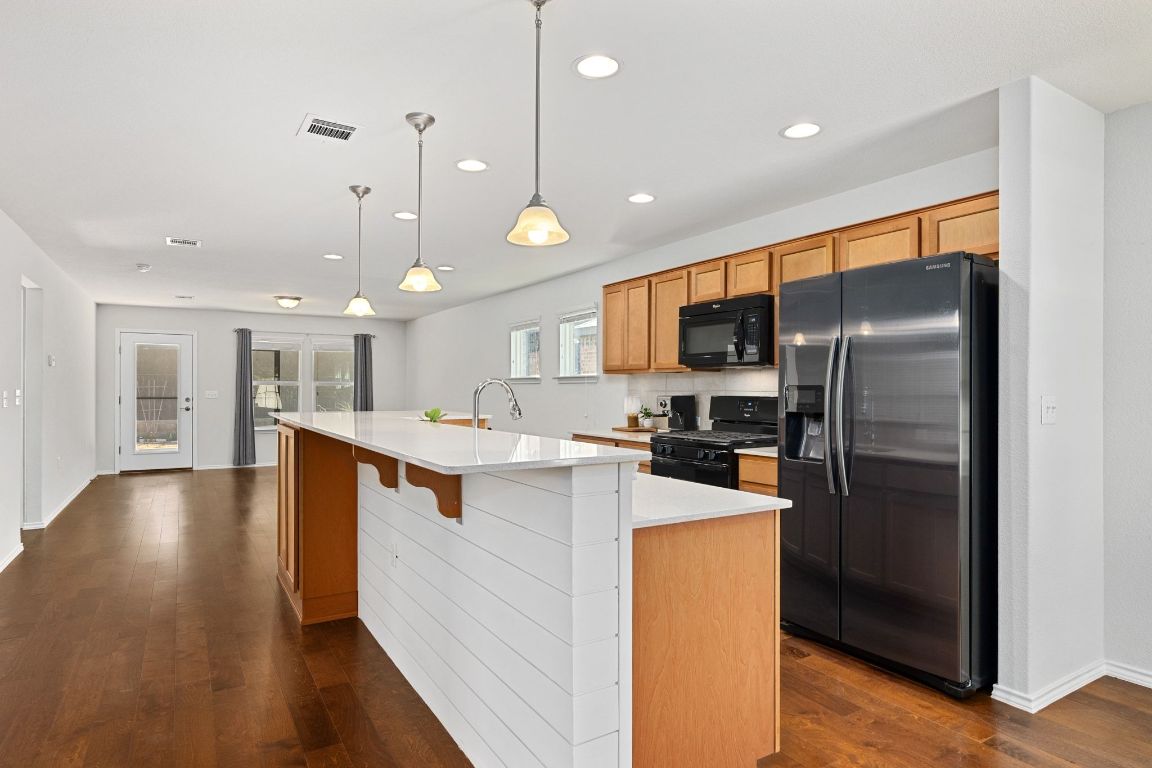 225 Hobby Street Georgetown, TX 78633 - Photo 7 of 40 a kitchen with stainless steel appliances granite countertop a refrigerator a sink dishwasher a oven and a dining table with wooden floor