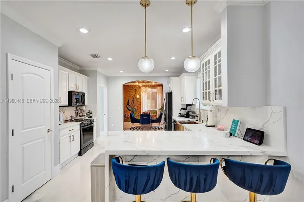 a kitchen with stainless steel appliances a stove top oven a refrigerator a sink and white cabinets