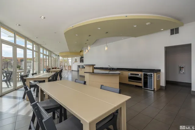 a dining hall with stainless steel appliances a dining table and chairs