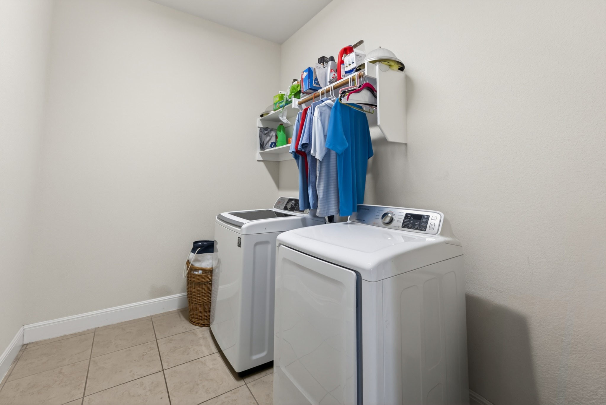 1017 Tabernash Leander, TX 78641 - Photo 34 of 38 Dedicated laundry area featuring tile flooring, neutral wall tones, white baseboards, and built-in shelving with an integrated hanging rod