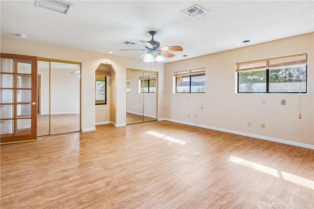 5975 Desert Star Road Johnson Valley, CA 92285 - Photo 22 of 74 an empty room with wooden floor chandelier fan and windows