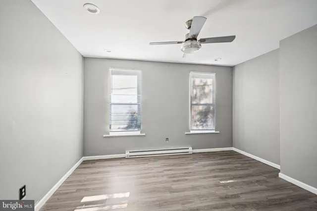 an empty room with wooden floor window and ceiling fan