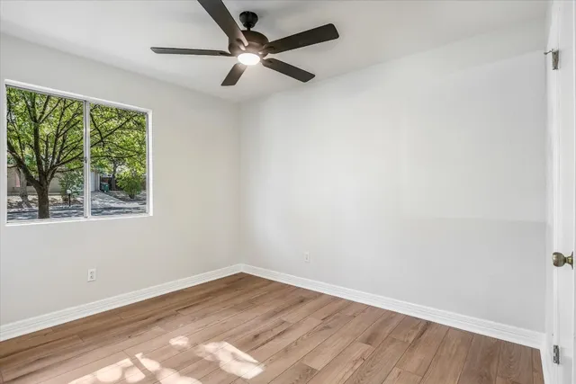 an empty room with a window and a ceiling fan