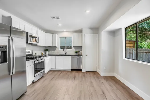 a kitchen with granite countertop a refrigerator oven a sink dishwasher and a stove with wooden floor