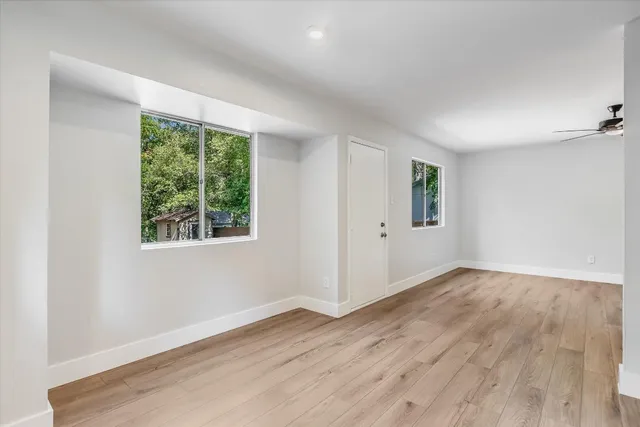 an empty room with wooden floor and windows