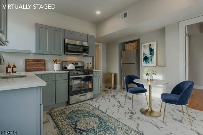 a kitchen with stainless steel appliances granite countertop a stove top oven a sink a dining table and chairs