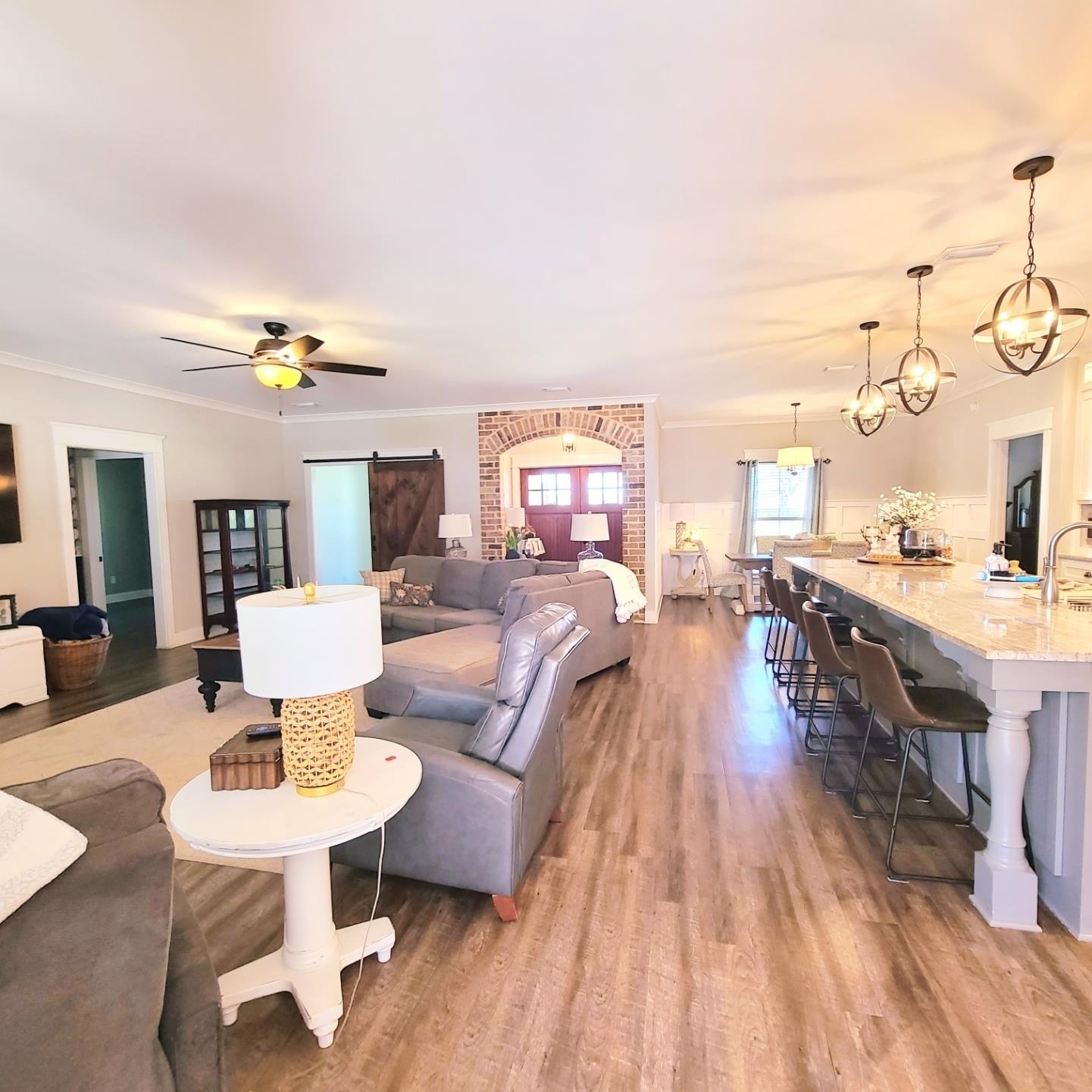 10051 Blackwell Nursery Road Semmes, AL 36575 - Photo 42 of 54 Living area with a barn door, light wood-style flooring, ornamental molding, ceiling fan, and arched walkways