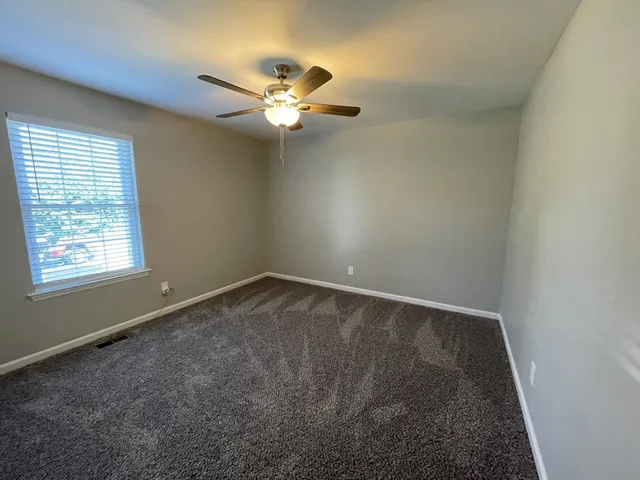 an empty room with a window and a fan